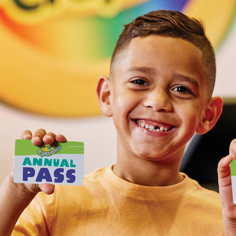 Image of a young boy smiling and holding a Crayola Experience Annual Pass