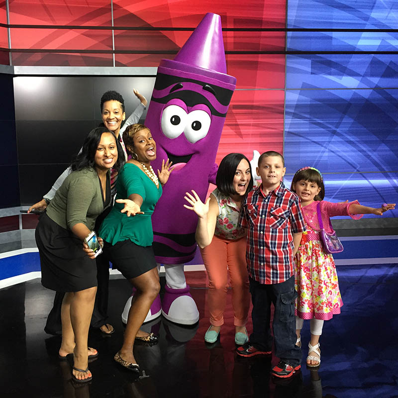Kids and adults posing with a giant costumed crayon character