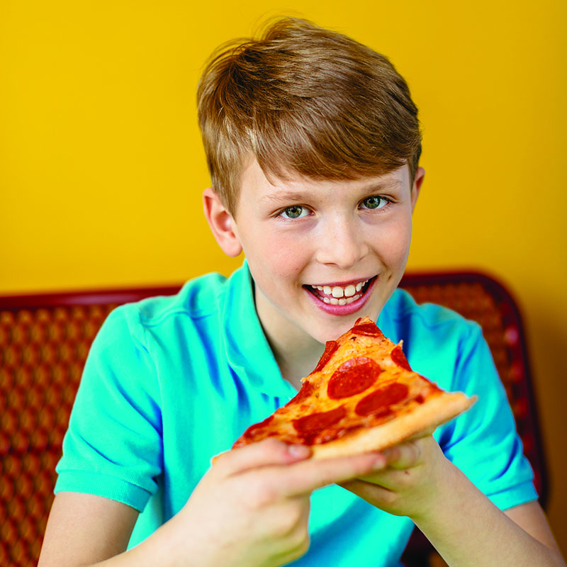 A boy eating pepperoni pizza