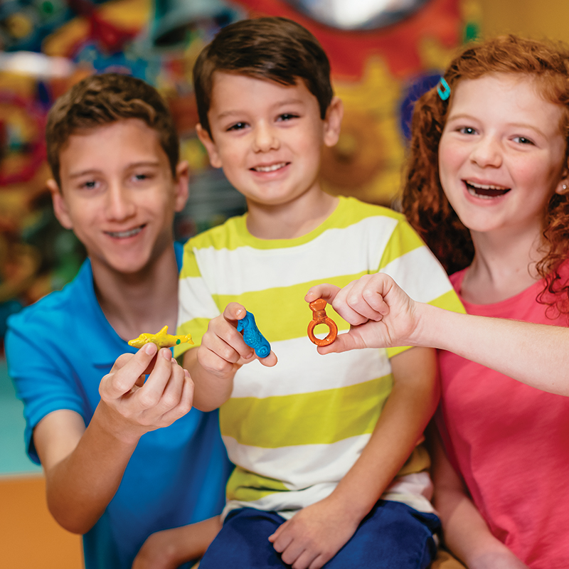 Three children holding their Melt and Mold creations