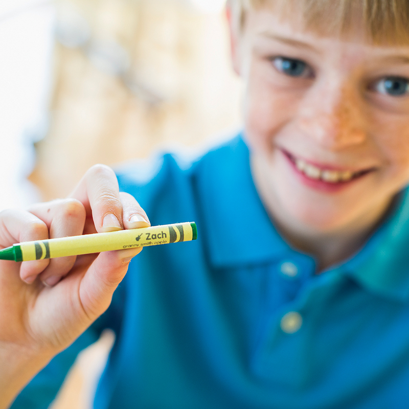 Young boy holding a green crayon