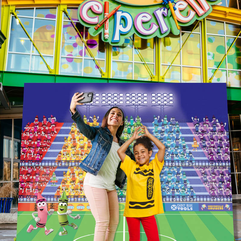 Family posing in front of a banner outside of Crayola Experience 
