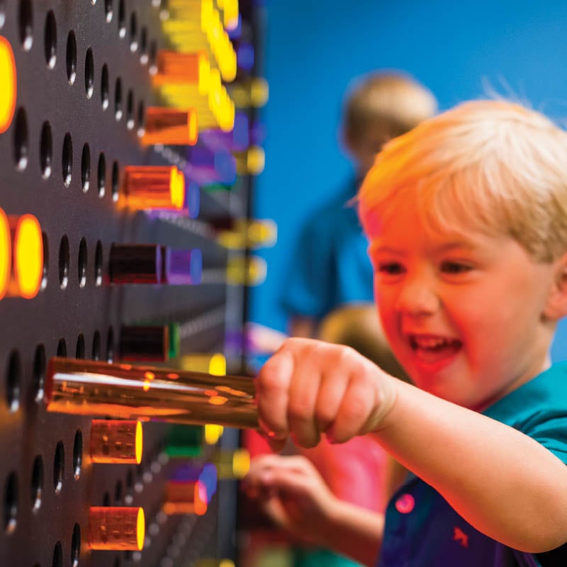Child putting pegs into light brite board.