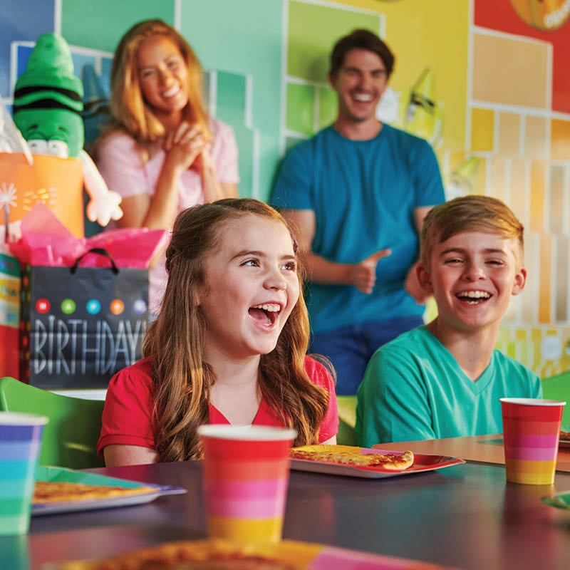 Child smiling surrounded by family during a colorful birthday party