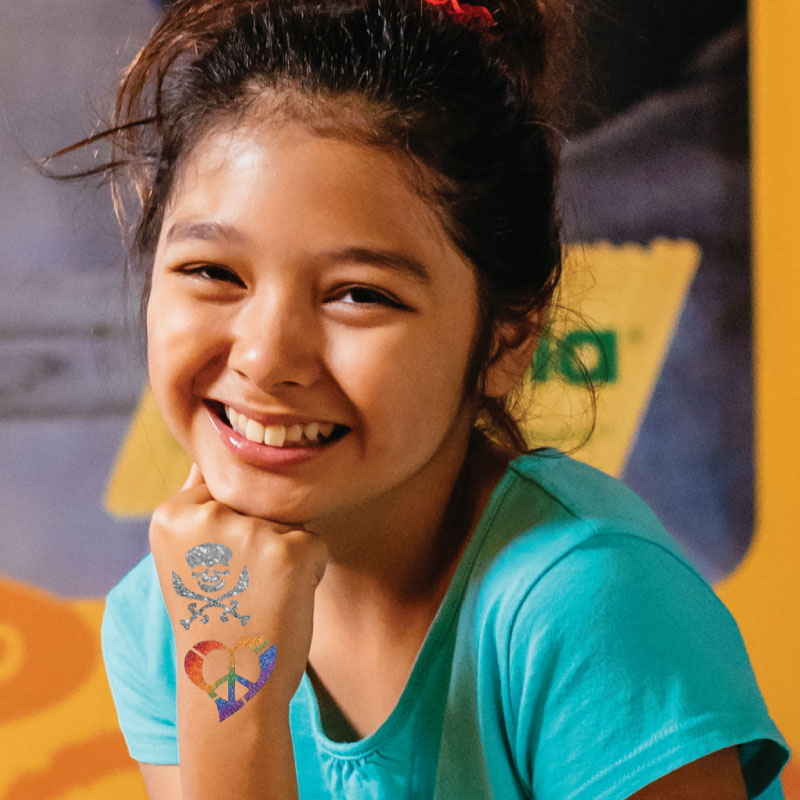 Child showing two glitter tattoos on her hand