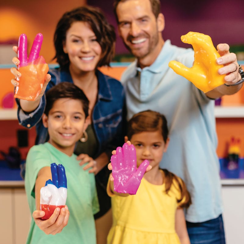 Family holding out colorful wax hands souvenirs