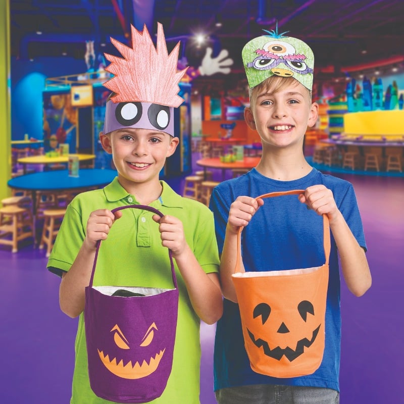 Two kids holding up trick or treat buckets